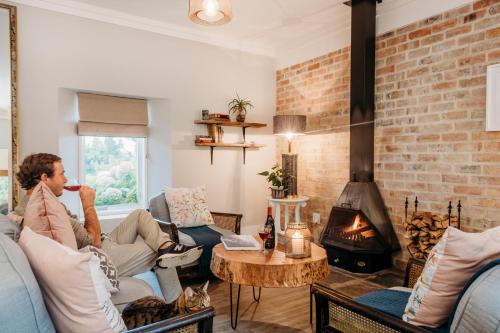 a man sitting on a couch in a living room with a fireplace at White Water Farm in Stanford