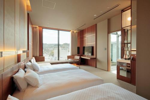 a hotel room with two beds and a television at Candeo Hotels Nagasaki Shinchi Chinatown in Nagasaki
