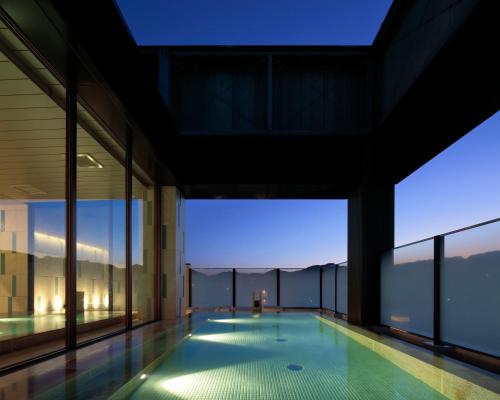 a swimming pool in a building with large windows at Candeo Hotels Nagasaki Shinchi Chinatown in Nagasaki