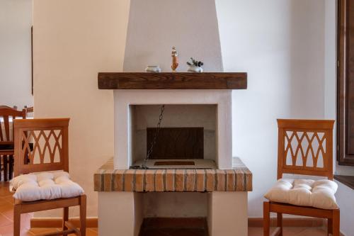a living room with a fireplace with two chairs at Ginepro Poderone in Grosseto