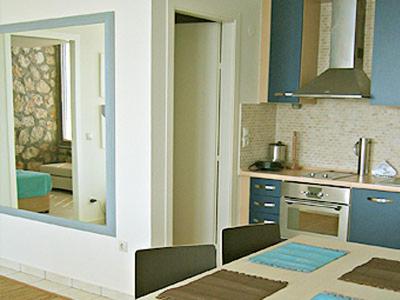 eine Küche mit blauen Wänden, einem Tisch und einem Spiegel in der Unterkunft Villa Brio in Skala
