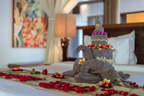 a toy elephant sitting on a bed with flowers at Surya Kembar Villas in Ubud