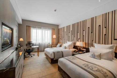 a hotel room with two beds and a television at Grand Pacific Hotel Ningbo in Yuyao