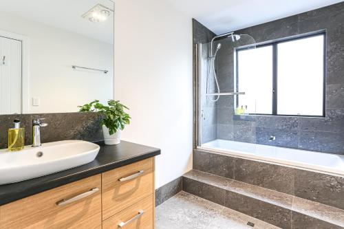 Un baño con lavabo, bañera y espejo. en Karri Forest Vista-peaceful home with forest views, en Margaret River Town