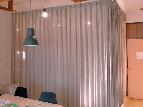 a room with a table and a large curtain at Saga International Guesthouse Hagakure in Saga