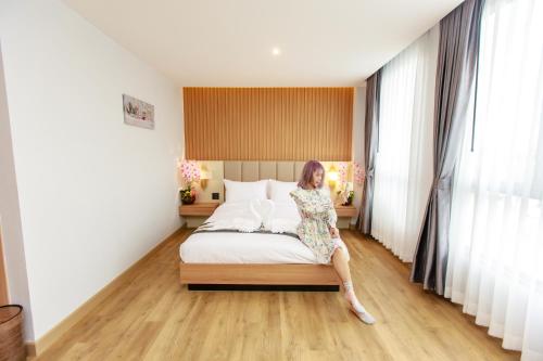 a woman sitting on a bed in a room at Siri Hotel Lumphun in Ban Pa Daet