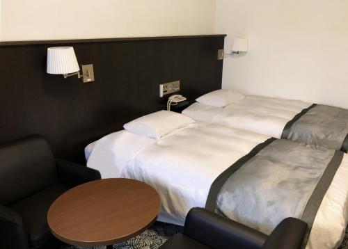 a hotel room with two beds and a table at Art Hotel Narita in Narita