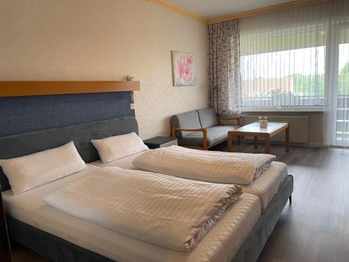 a hotel room with two beds and a chair at Seehotel Geestland in Bad Bederkesa