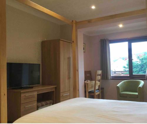 a bedroom with a bed and a tv and a window at Island View House in Ullapool