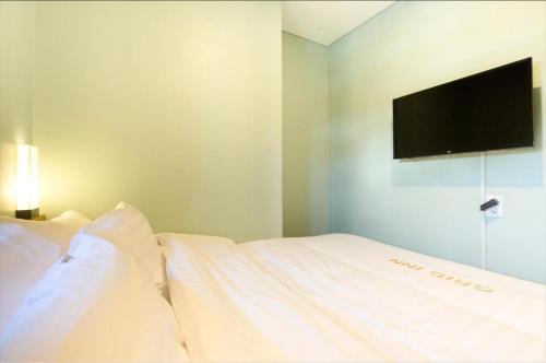 a bedroom with a white bed with a flat screen tv at Grid Inn Hotel in Seoul