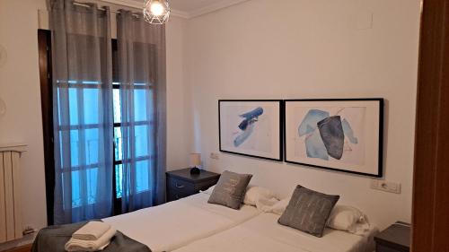 a bedroom with two beds and two pictures on the wall at 4AgostoPlace in Zaragoza