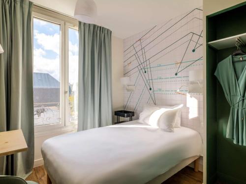 una camera da letto con un grande letto bianco e una finestra di ibis Styles Asnieres Centre ad Asnières