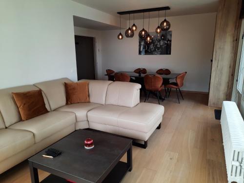 a living room with a white couch and a table at Lichtrijk en comfortabel hoekappartement met gratis parking en zeer centraal gelegen - Comme Chez Soi in Ostend