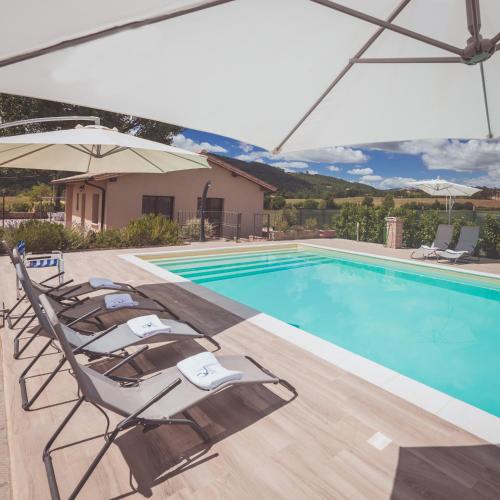 a swimming pool with lounge chairs and an umbrella at Agriturismo Querceto in Frazione Mocaiana