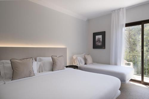 two white beds in a room with a window at Hotel Montjoi by Brava Hoteles in Sant Feliu de Guixols