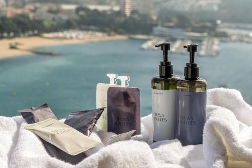 3 bottiglie di vino sedute su un asciugamano con una spiaggia di Hotel Montjoi by Brava Hoteles a Sant Feliu de Guíxols