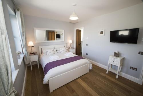 a white bedroom with a bed and a tv at Clach Gorm in Stornoway