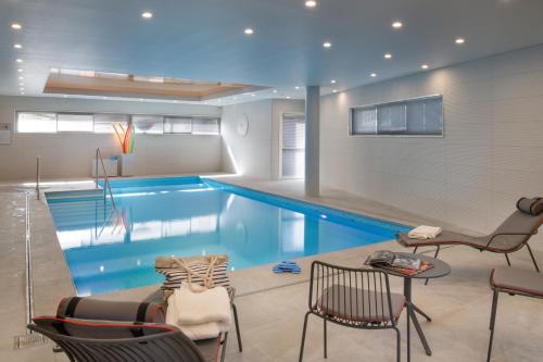 - une piscine dans une pièce avec des chaises et une table dans l'établissement DOMITYS Les Mosaïques, à Rouen
