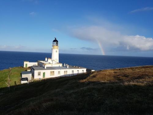 a lighthouse on a hill with a rainbow in the background at Clach Gorm in Stornoway