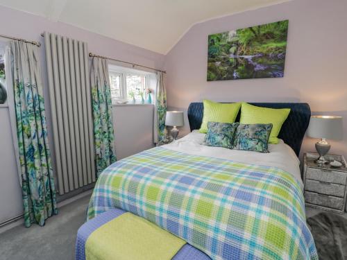 ein Schlafzimmer mit einem Bett und zwei Fenstern in der Unterkunft White Roses Retreat in Betws-y-coed