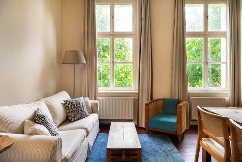 a living room with a couch and a table and windows at numa I Belfort Rooms & Apartments in Berlin