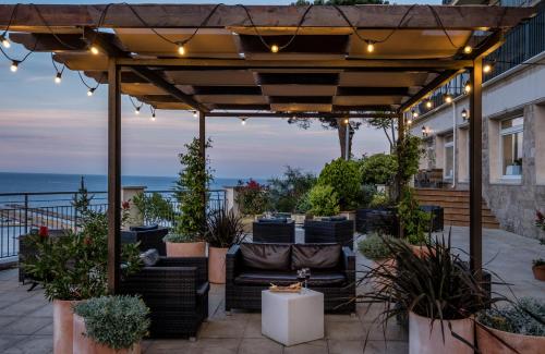 a patio with a pergola and chairs and plants at Hotel Montjoi by Brava Hoteles in Sant Feliu de Guixols