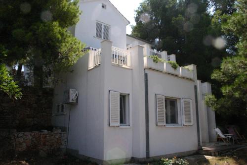 een wit huis met witte ramen en een hek bij Cozy Jelsa apartment in the shade of the pines. in Jelsa