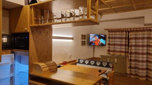 una cucina con tavolo in legno e TV a parete di Casa Cortina - presso Sussy Residence a Falcade