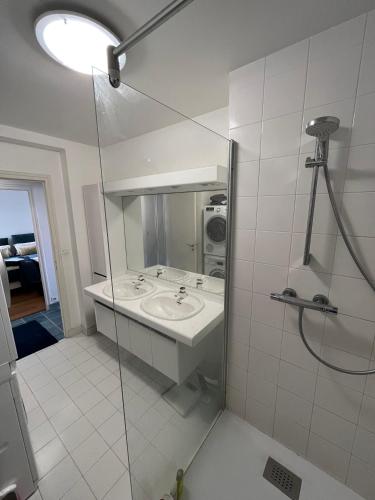 une salle de bain blanche avec un lavabo et une douche dans l'établissement Appartement - vue mer, à Concarneau