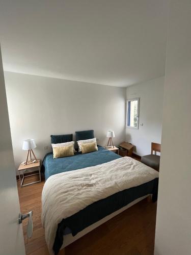 une chambre avec un grand lit avec des draps bleus dans l'établissement Appartement - vue mer, à Concarneau