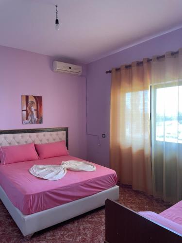 um quarto com uma cama com lençóis cor-de-rosa e uma janela em Aragosta Shengjin 2 em Shëngjin