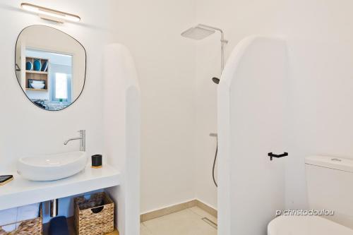 Baño blanco con lavabo y espejo en Agnantema luxury suites en Kárpatos