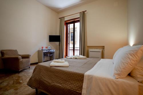 a bedroom with a bed and a chair and a window at La Loggia di Trapani in Trapani