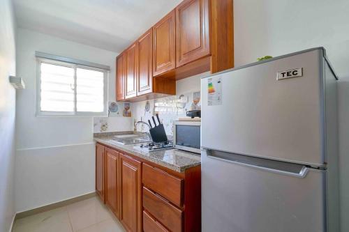 a kitchen with a white refrigerator and wooden cabinets at Escape Studio Apartment Close to Agora Mall in Santo Domingo