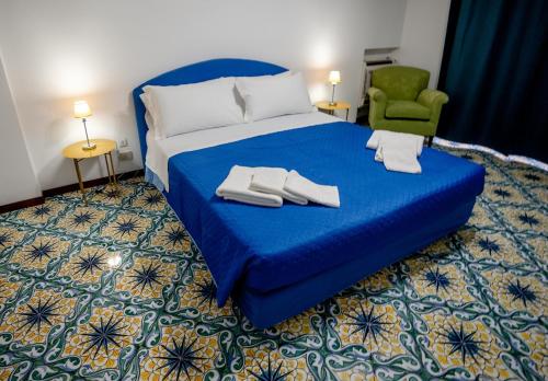 a bedroom with a blue bed and a green chair at La Loggia di Trapani in Trapani