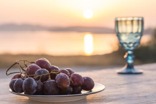 a plate of grapes on a table with a wine glass at Amato in Mandrakia