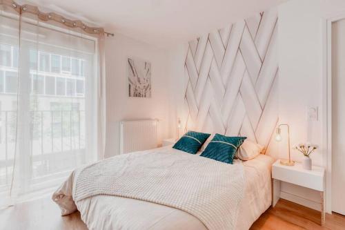 biała sypialnia z dużym łóżkiem z zielonymi poduszkami w obiekcie L'élégant portes de Paris- Parking-5'RER B w mieście Gentilly