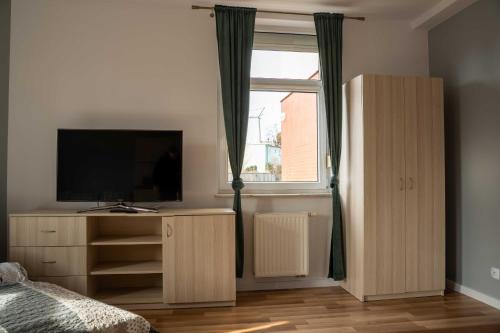 una camera da letto con un letto, una tv e una finestra di Apartamenty Na Winklu Green a Unieście