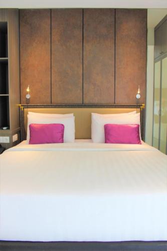 a bedroom with a large bed with two pink pillows at Shakti Hotel Bandung in Bandung