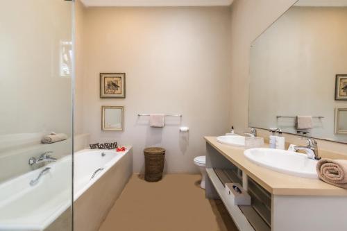 a bathroom with two sinks and a tub and a mirror at Nguni Cottage at Ngoye Lodge in Mtunzini