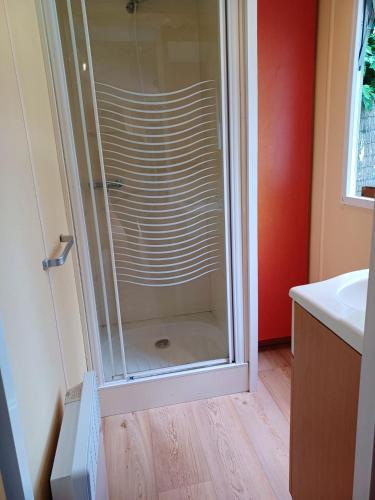 La salle de bains est pourvue d'une douche en verre et d'un lavabo. dans l'établissement Charmant bungalow à Saint-Pierre-d'Oléron - Jardin privé, à Saint-Pierre-dʼOléron