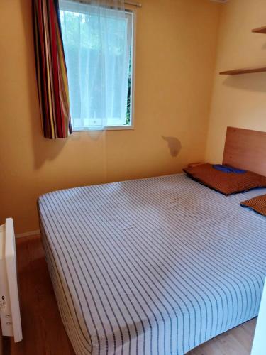 une chambre avec un grand lit avec une fenêtre dans l'établissement Charmant bungalow à Saint-Pierre-d'Oléron - Jardin privé, à Saint-Pierre-dʼOléron