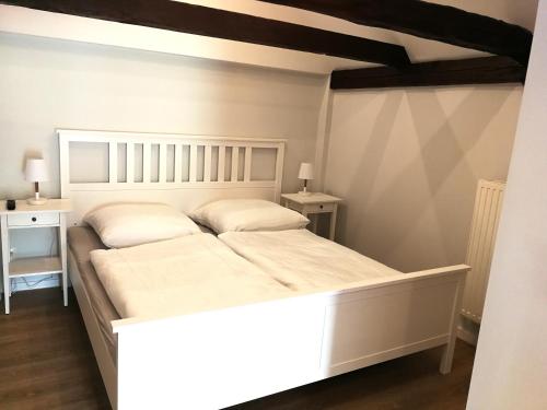 um quarto com uma grande cama branca com duas mesas de cabeceira em Pension Schlossblick Thallwitz em Thallwitz