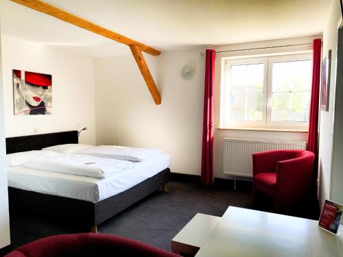 a hotel room with a bed and a red chair at Landhotel Zerlaut in Kißlegg