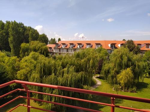 a building with a red fence next to a garden at Cserke-Thermál Apartman in Cserkeszőlő