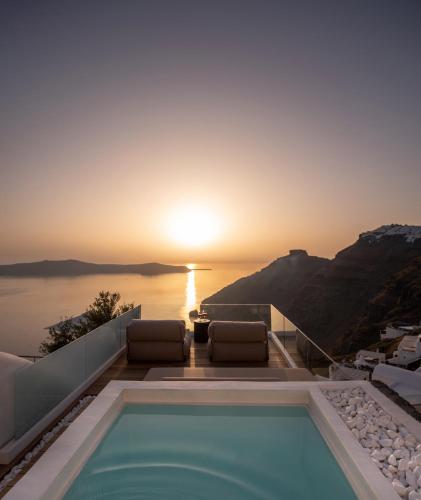 a pool with a view of the ocean at sunset at Agnadema Apartments in Firostefani