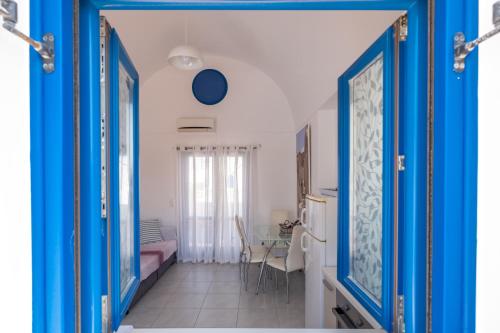 a hallway with blue doors and a room with a table at Adelphi Apartments in Perissa