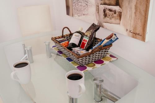 a basket on a bathroom counter with two cups of coffee at Adelphi Apartments in Perissa