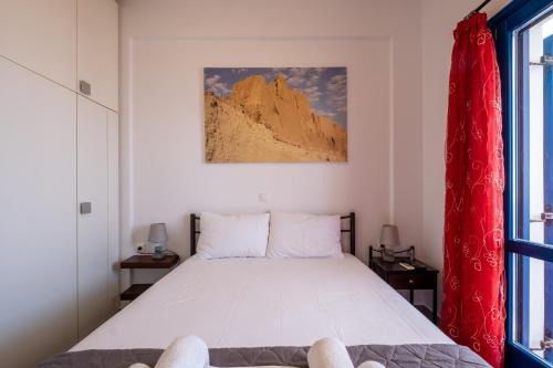 a bedroom with a large bed with a red curtain at Adelphi Apartments in Perissa
