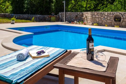 a bottle of wine sitting on a table next to a swimming pool at Villa Katarina in Rasopasno